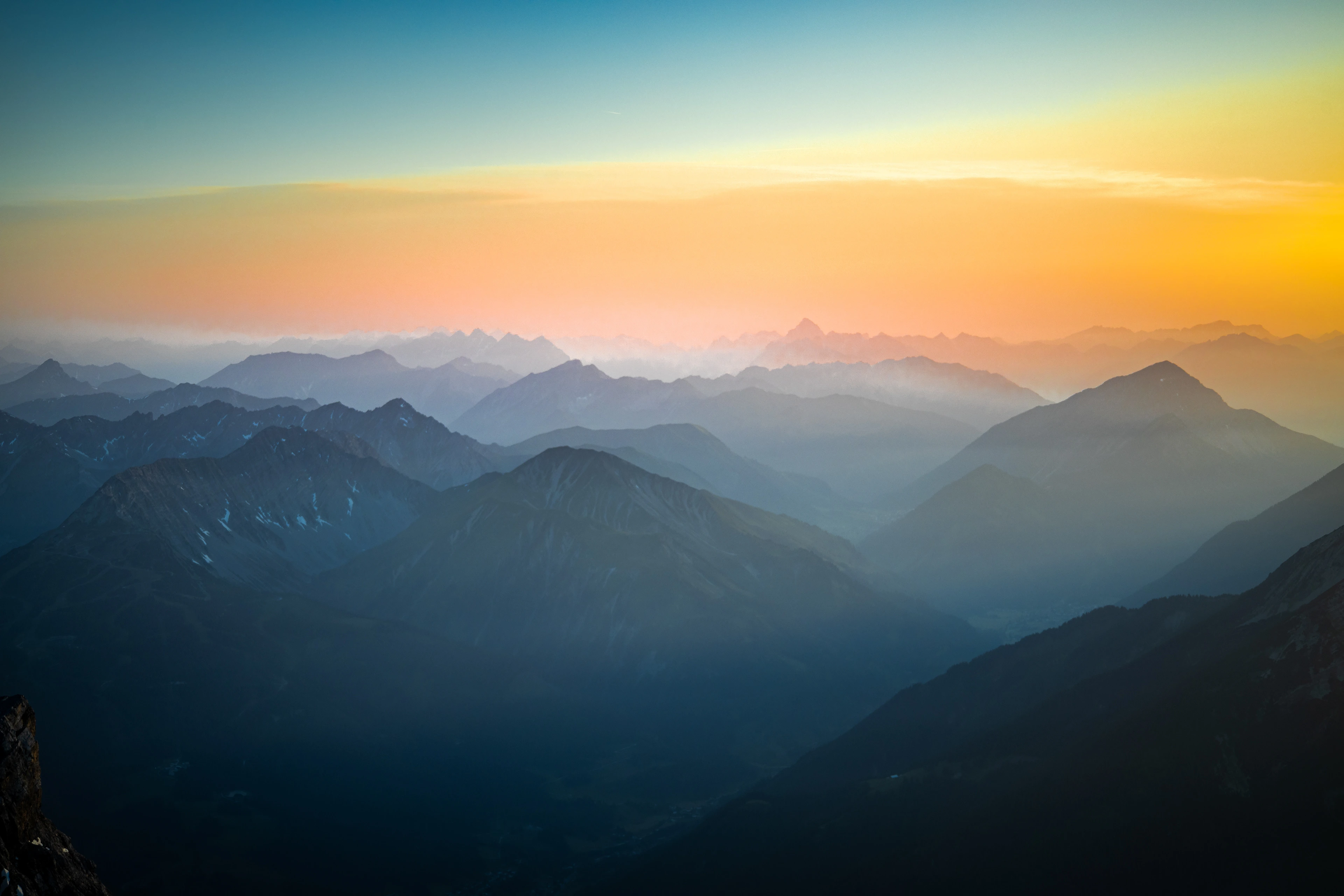 Weite Gebirgslandschaft in Schichten bei Sonnenuntergang mit Dunst in den Tälern.